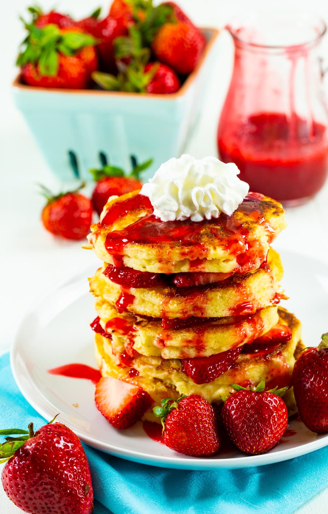 Strawberry Shortcake Pancakes on plate with fresh strawberries in background.
