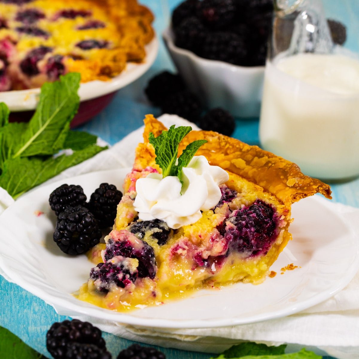 Slice of Blackberry Buttermilk Pie topped with whipped cream.