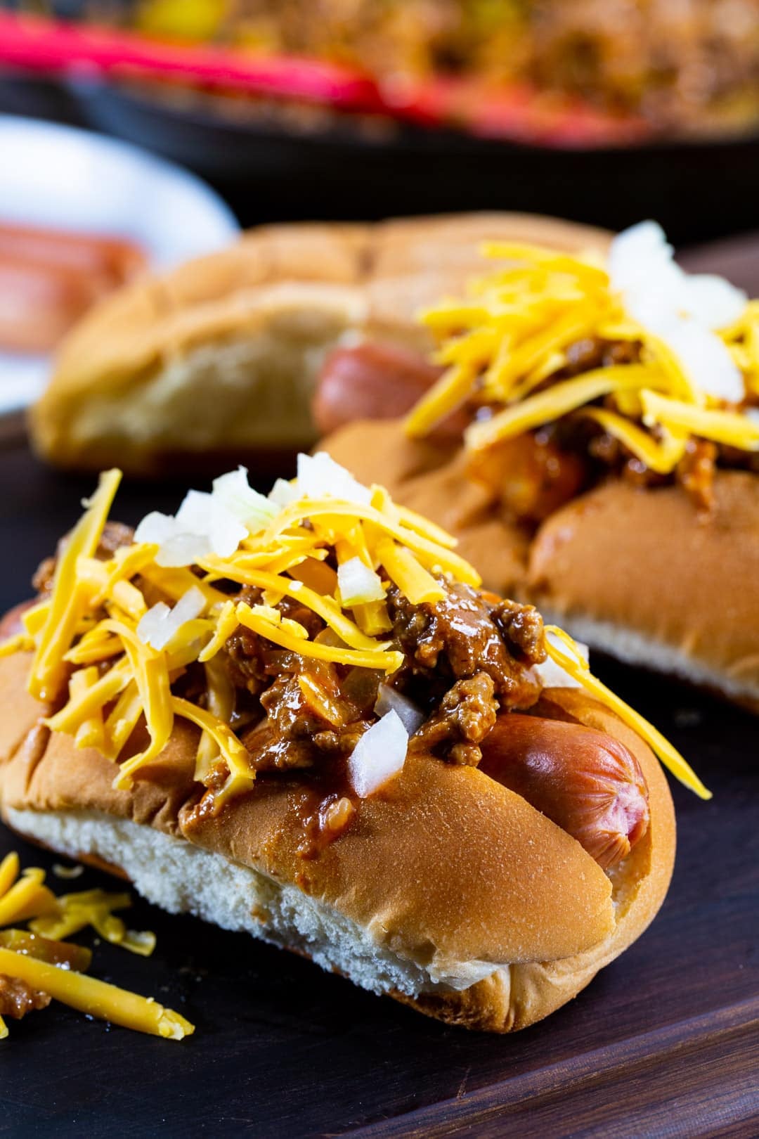 Hot Dogs topped with Sloppy Joe mixture on a wood serving board.