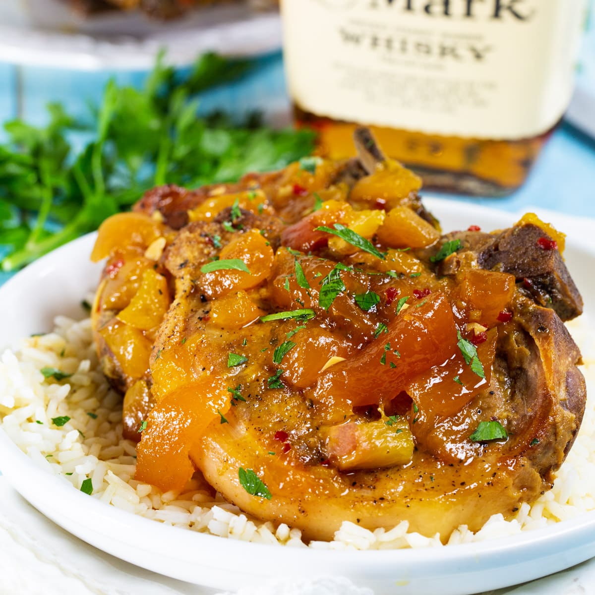 Slow Cooker Bourbon Peach Pork Chop over white rice on a plate.