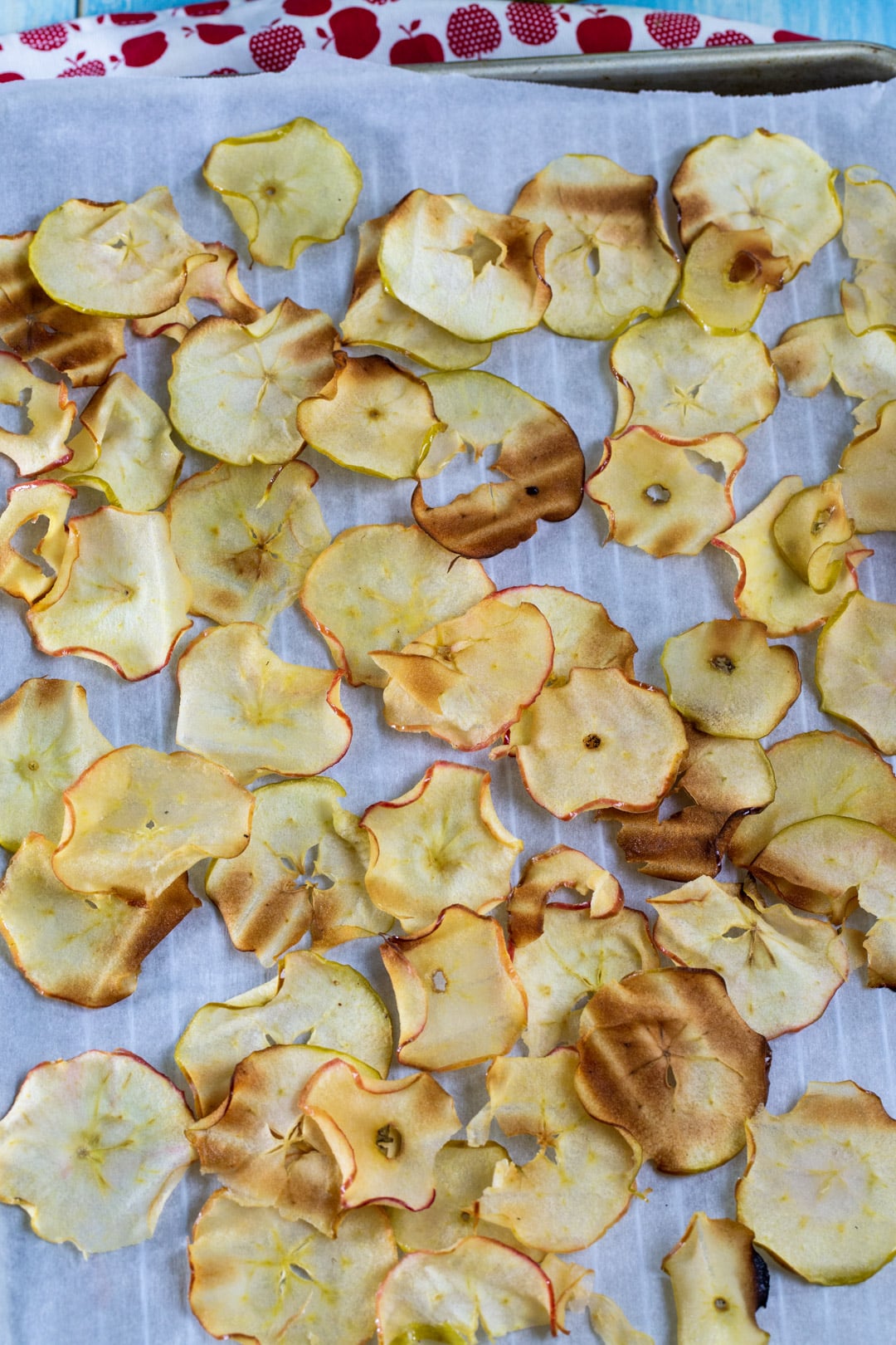 Cooked Apple chips on parchment paper-lined baking sheet.
