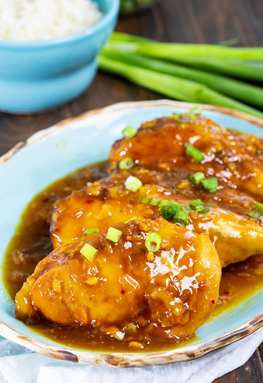 Slow Cooker Orange Chicken on serving plate and bowl full of rice.