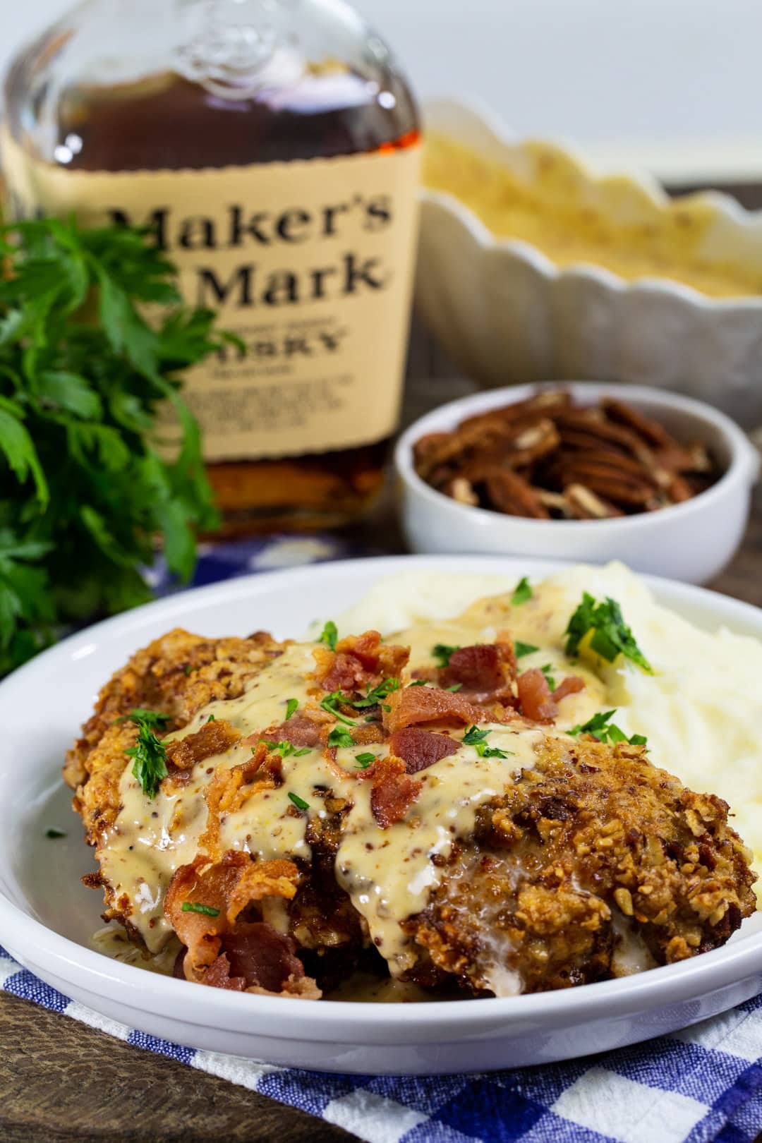 Finished chicken dish on a plate and bottle of bourbon.