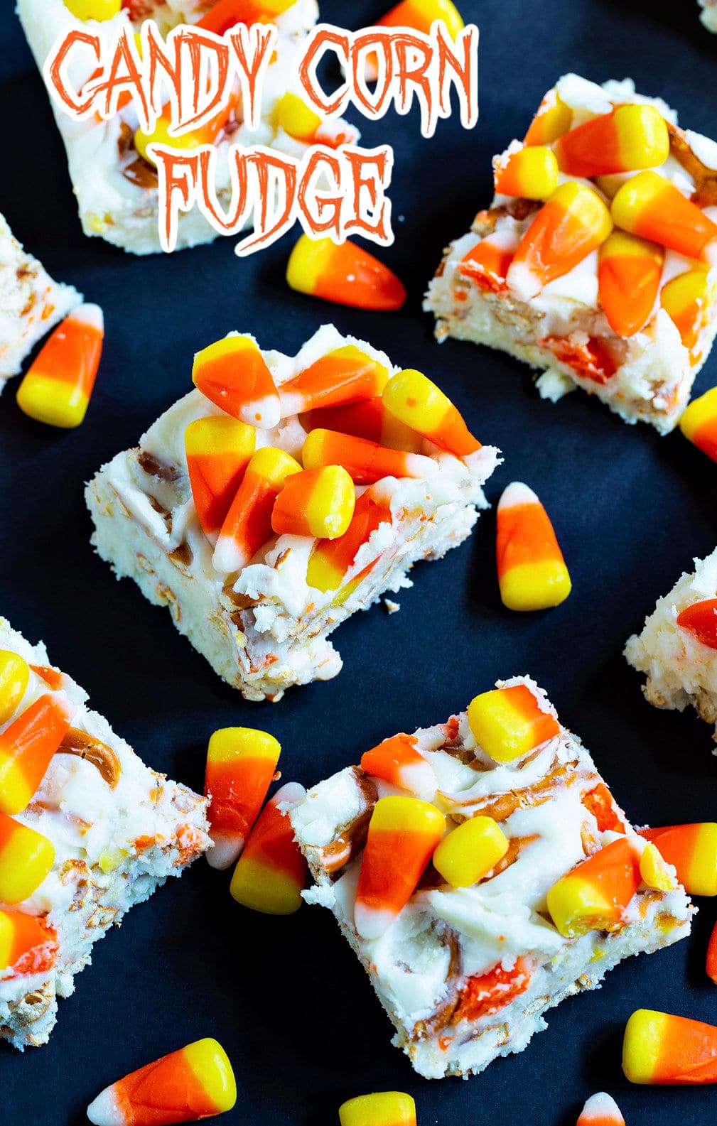 Squares of Candy Corn Fudge with pieces of candy corn scattered around them.