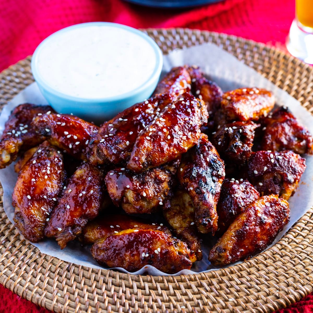 Crock Pot Sweet and Spicy Sticky Wings on a tray with bowl of dip.