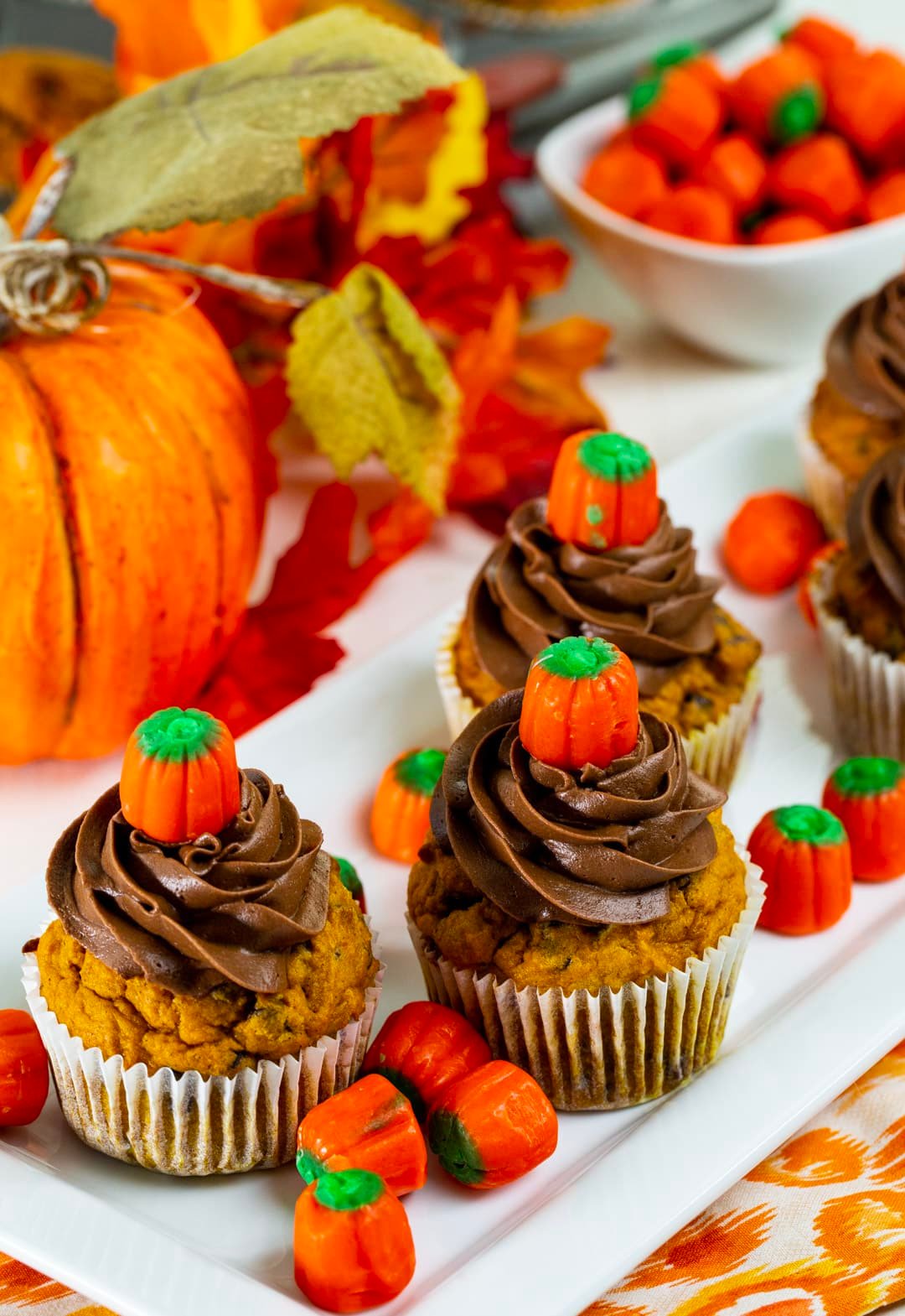 Pumpkin Chocolate Chip Cupcakes surrounded by candy corn pumpkins.