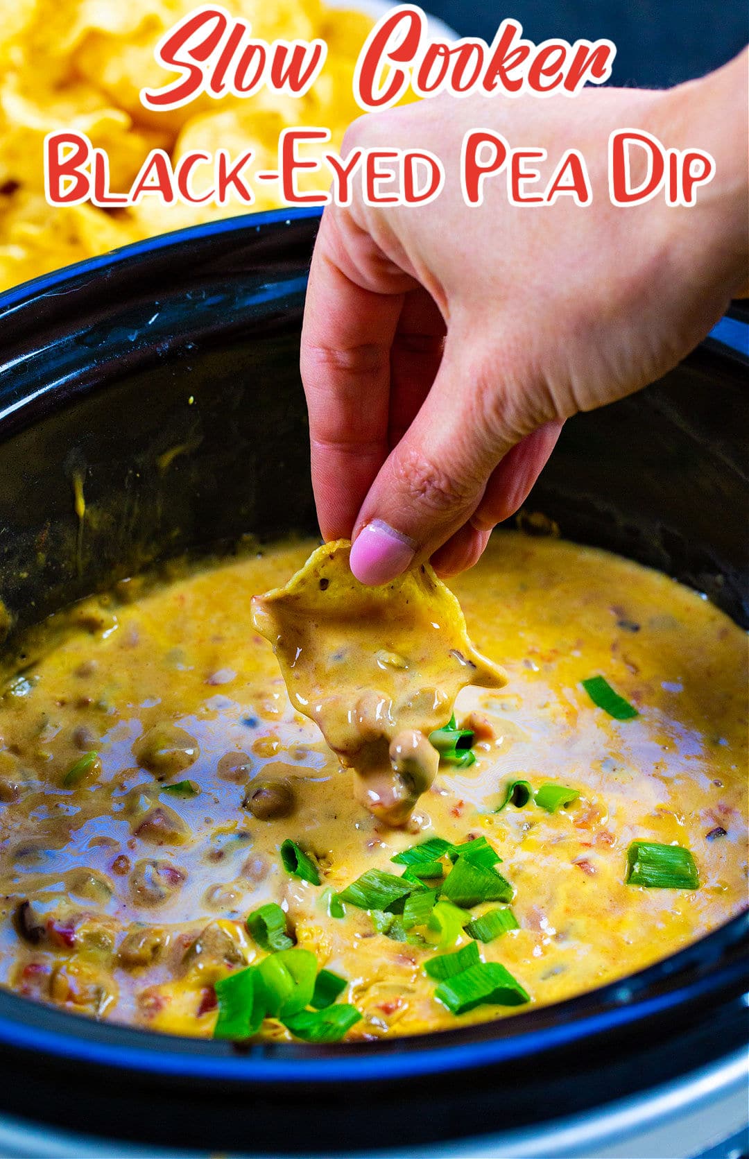Hand dipping chip into Slow Cooker Black-Eyed Pea Dip.