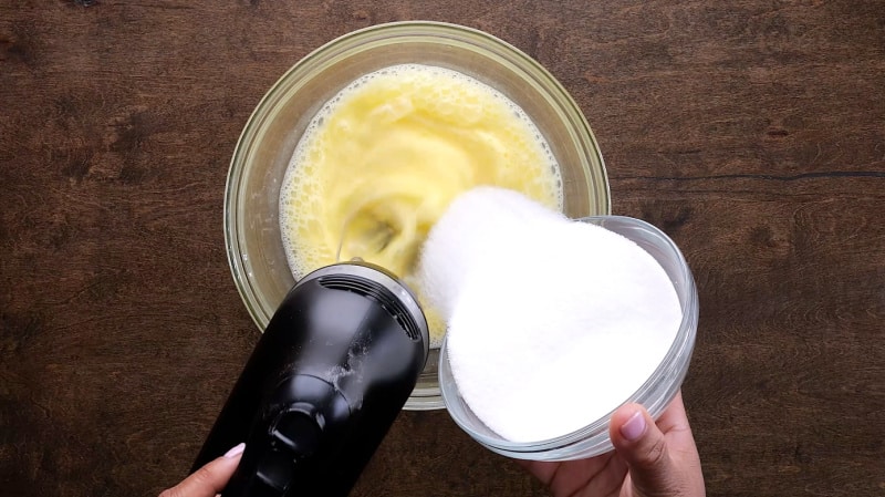Adding sugar into eggs.