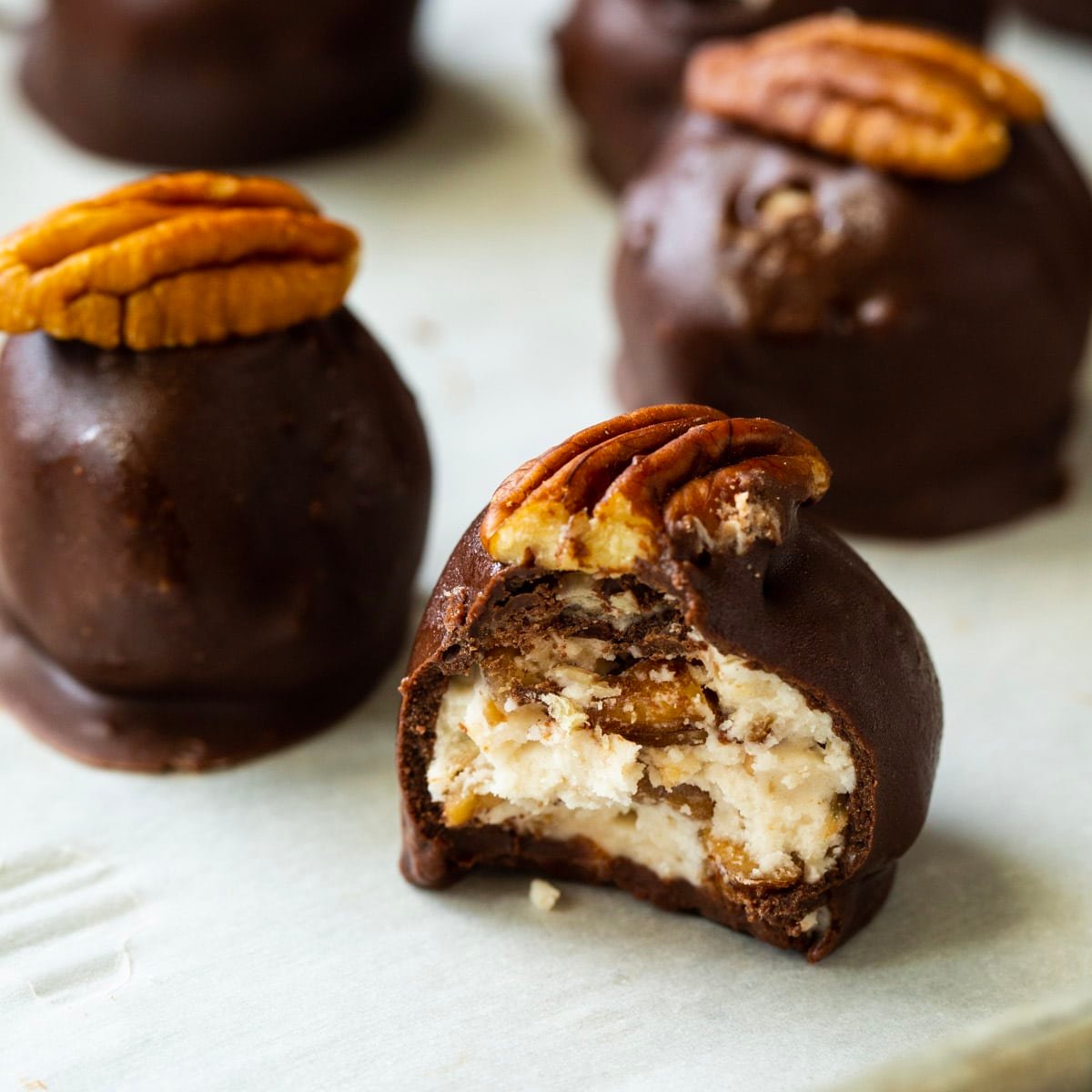 Bourbon Balls covered in chocolate and  topped with pecan halves.