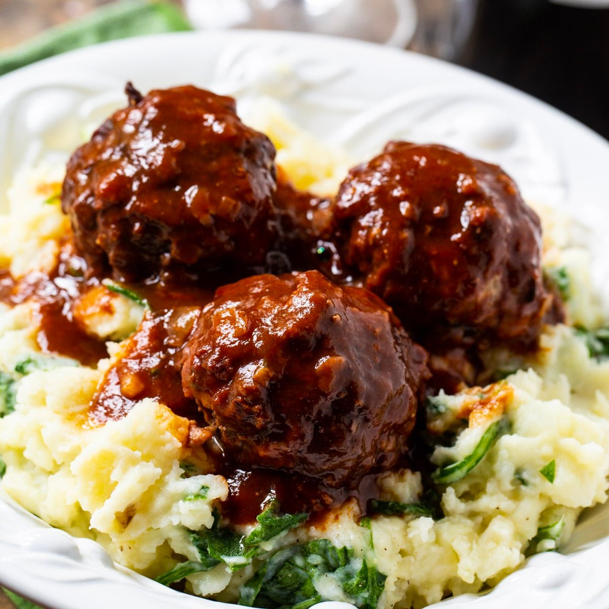 Three meatballs over spinach mashed potatoes.
