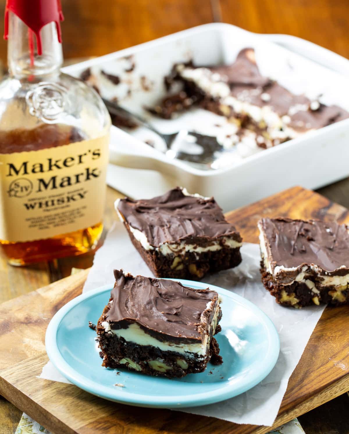 Double Frosted Bourbon Brownies arranged on wood cutting board.