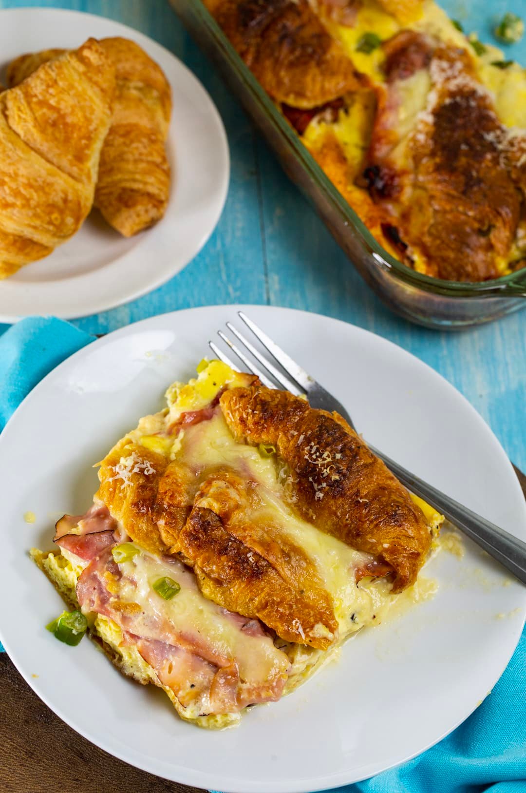 Stuffed Ham and Cheese Croissant Casserole on a plate and plate of croissants.