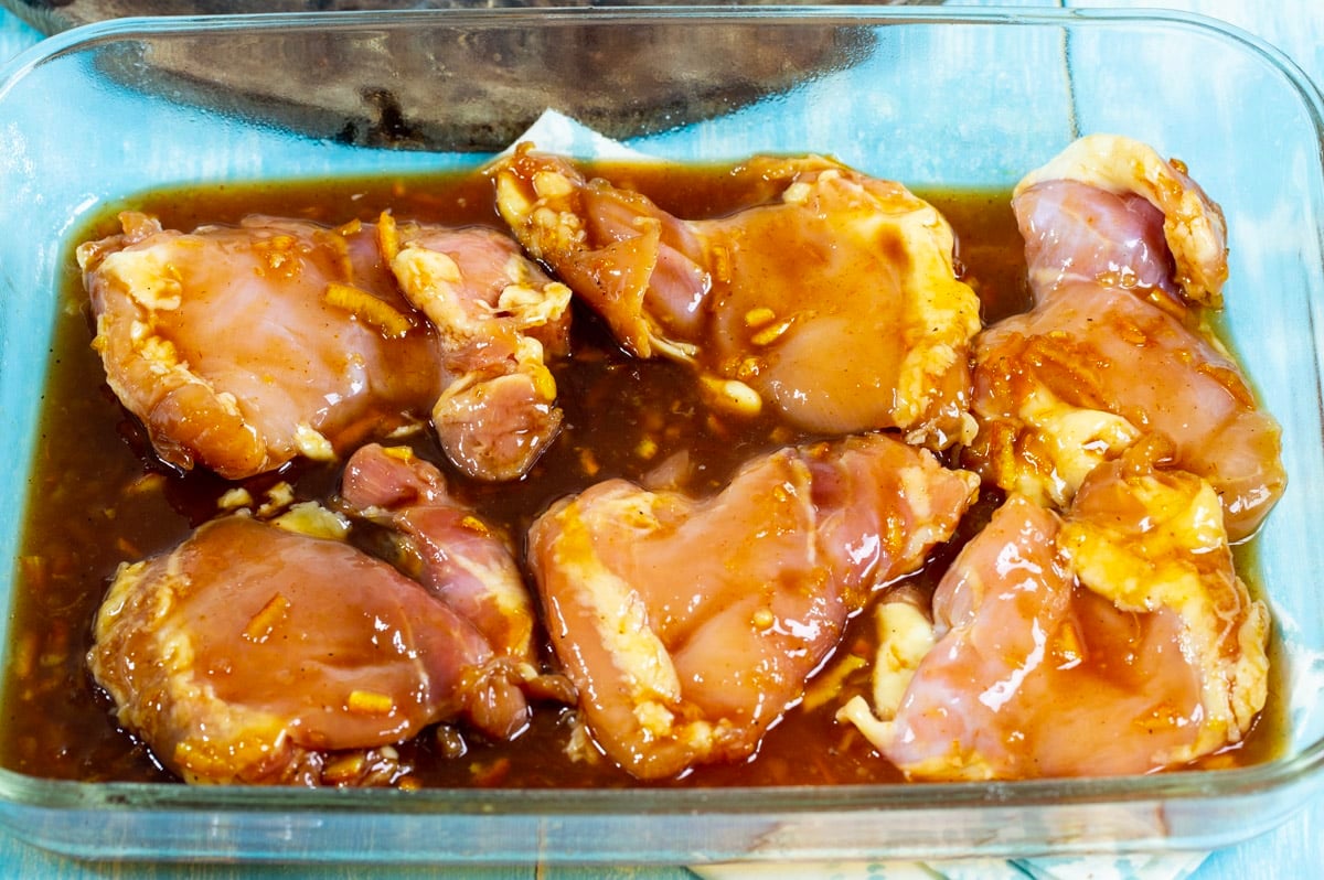 Uncooked chicken and marinade in baking dish.