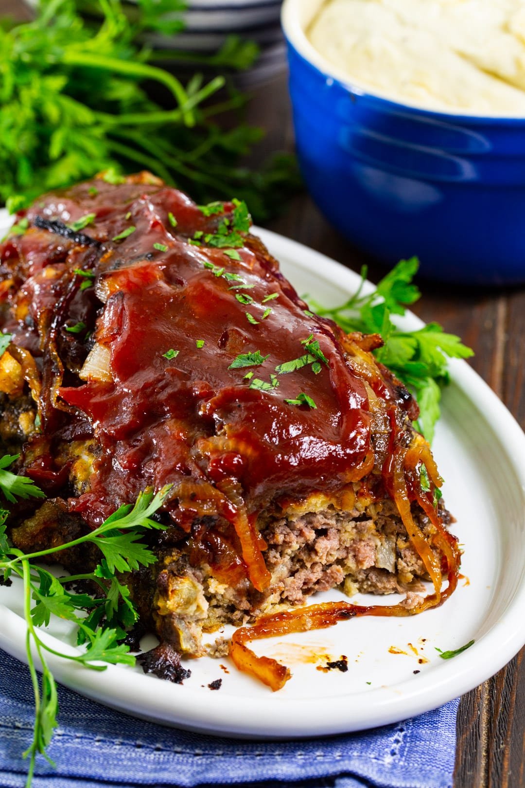 Meatloaf with a slice cut away and bowl of mashed potatoes.