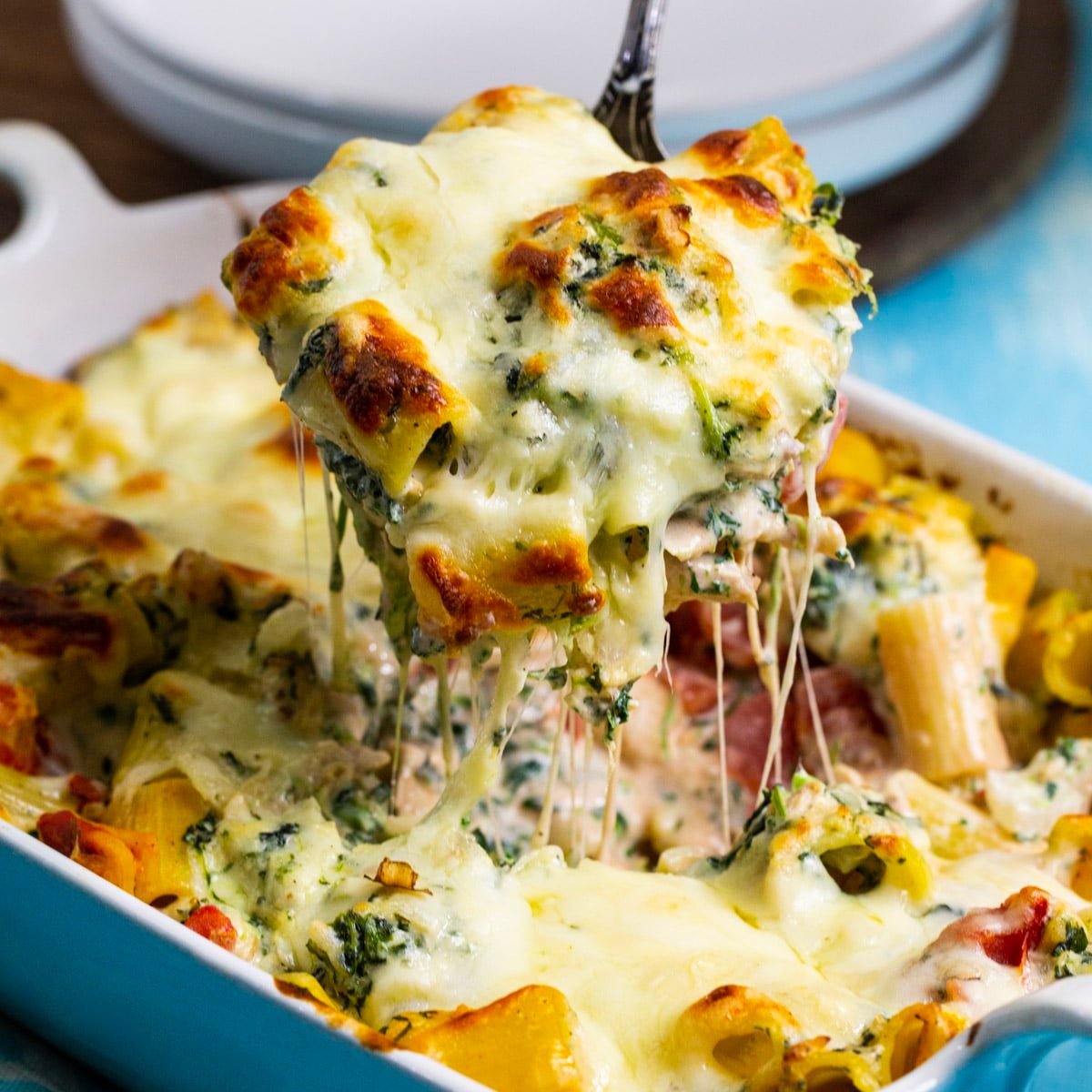 Spoon lifting Chicken Spinach Rigatoni out of baking dish.