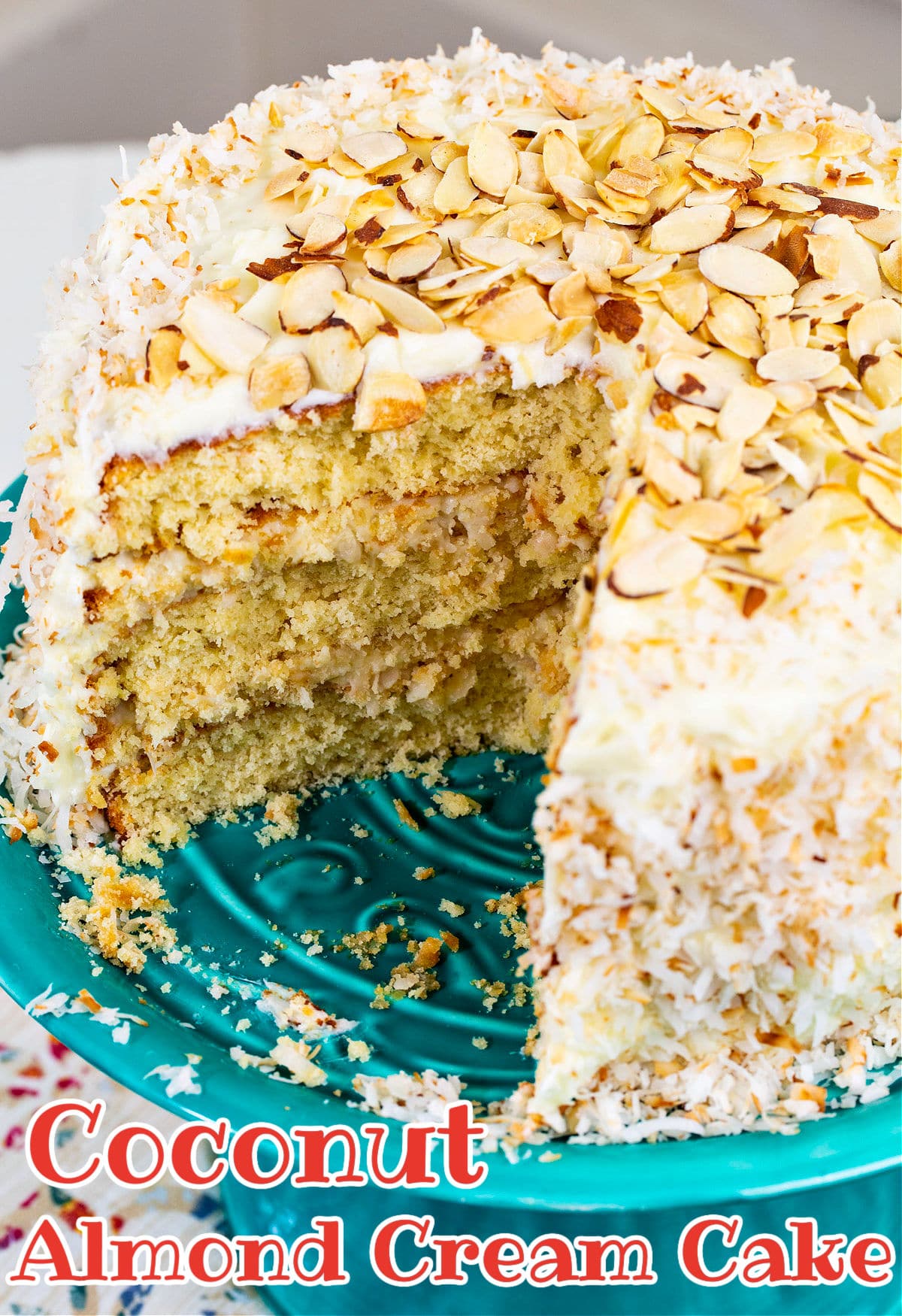 Coconut Almond Cream Cake with slice cut out of it.