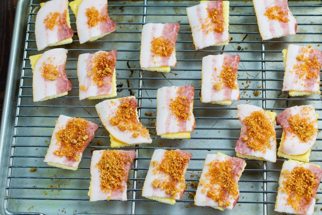 Uncooked bacon pieces on top of crackers.