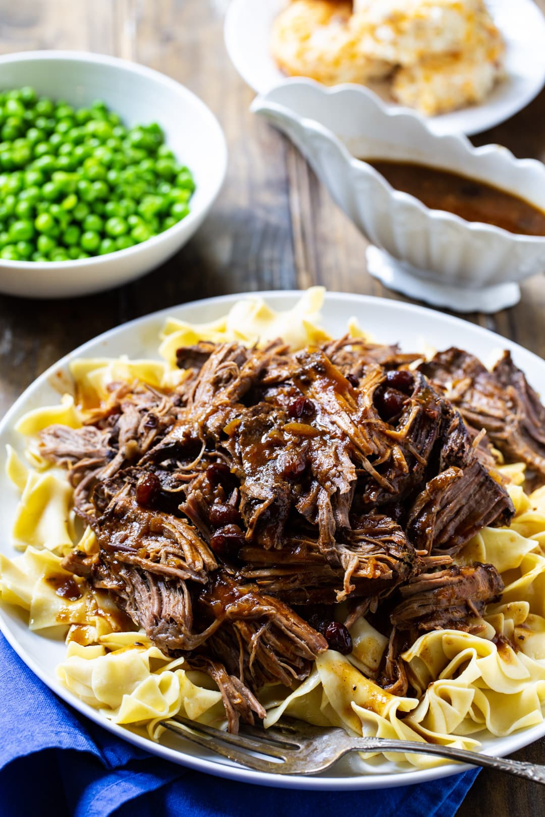 Pot Roast over buttered noodles and a bowl of peas.