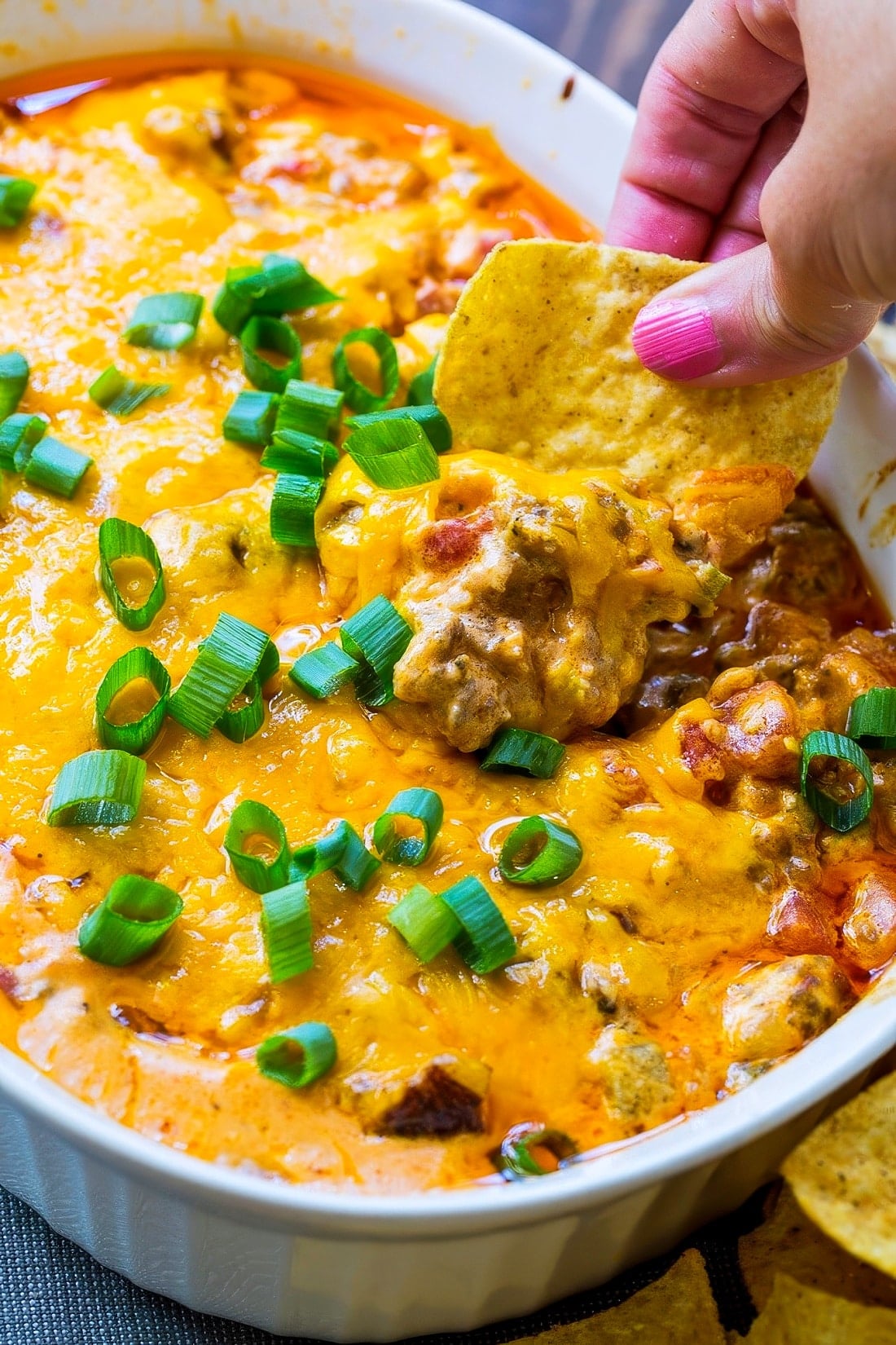 Chip scooping up Spicy Sausage Cheese Dip.