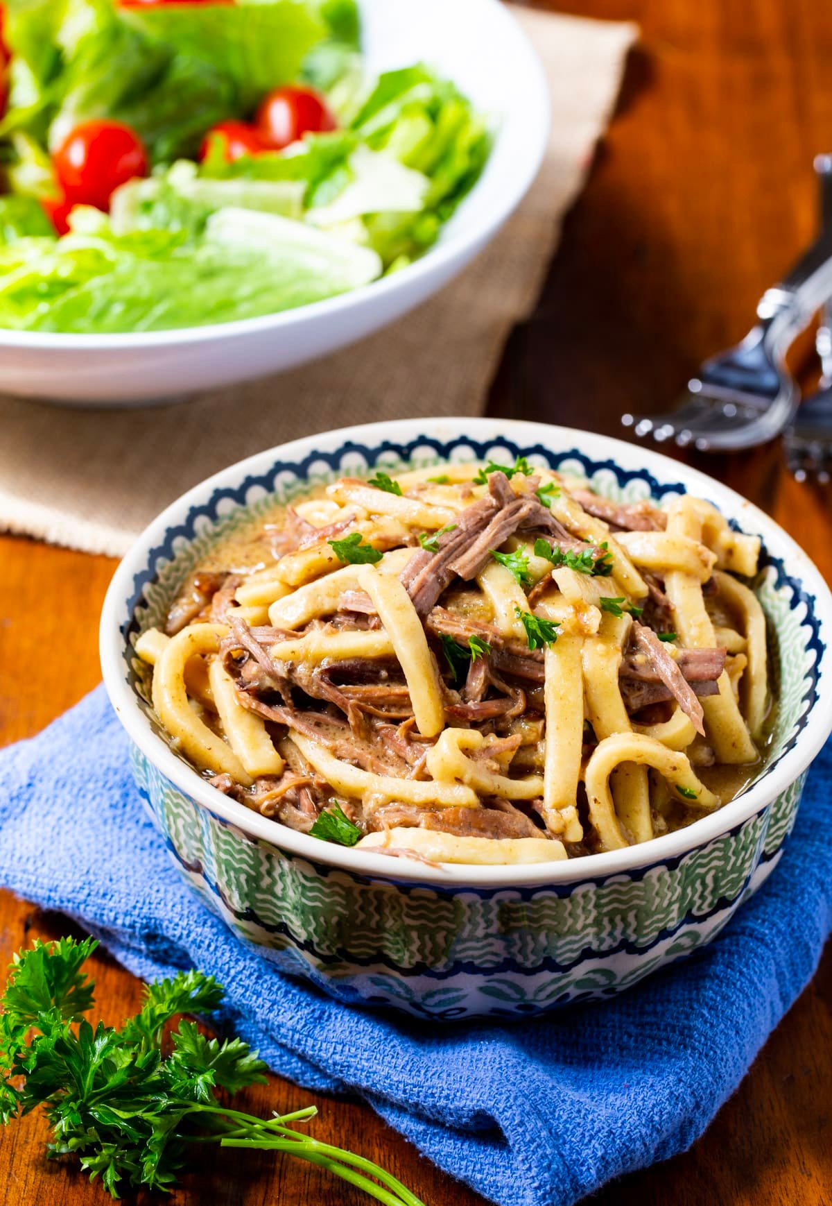 Beef and noodles in a bowl and a salad.