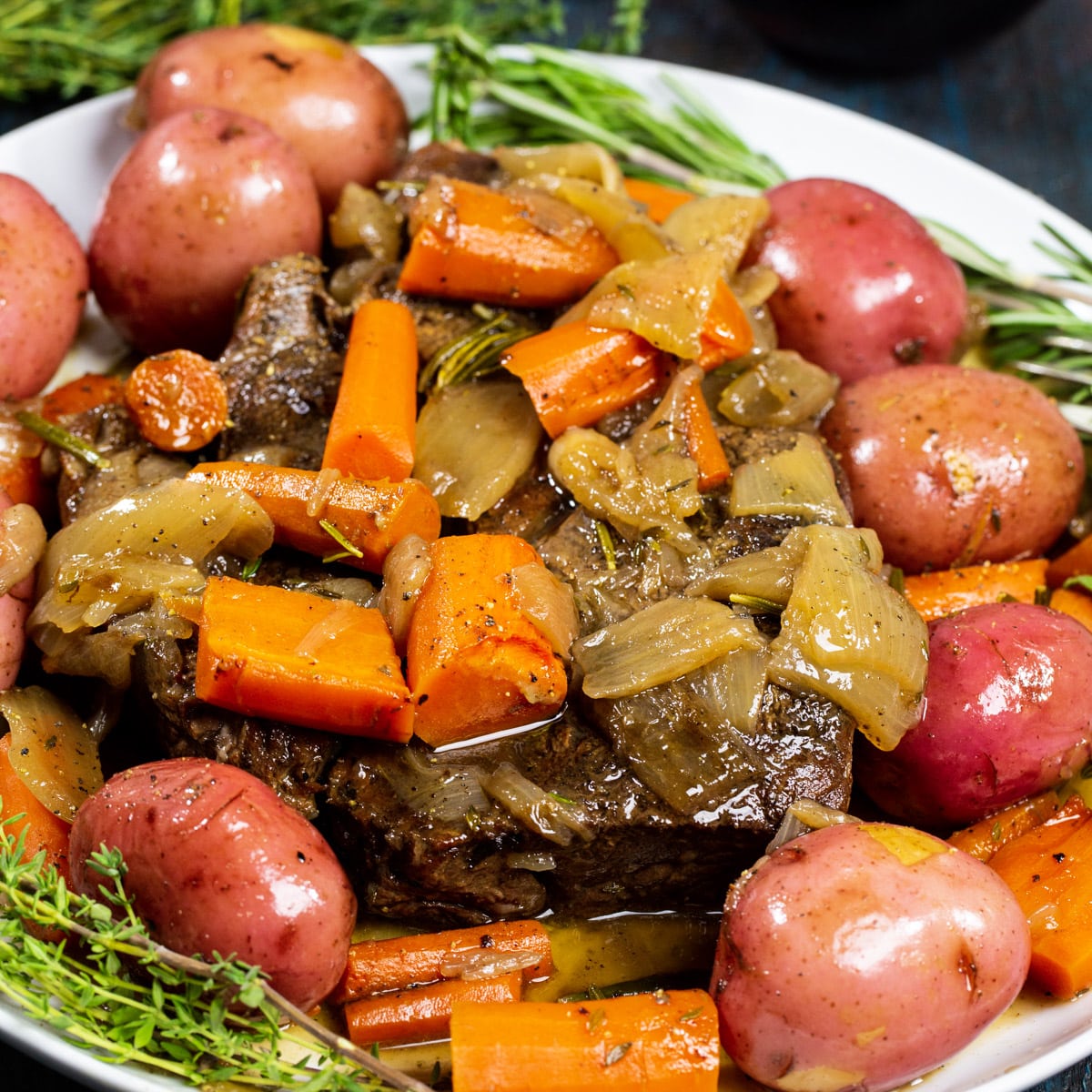 Pot Roast on serving platter with fresh herbs.