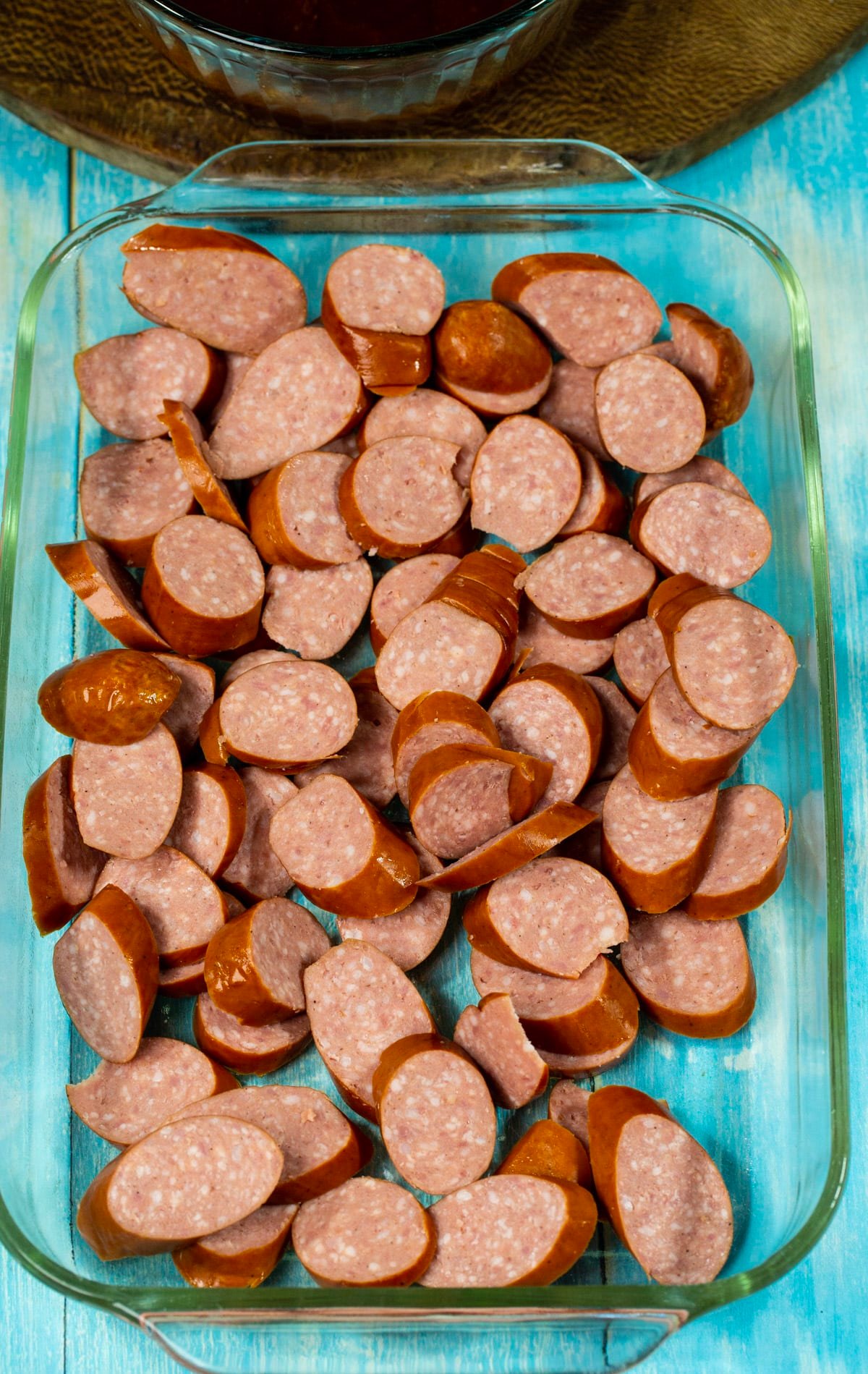 Uncooked sausage slices in baking dish.