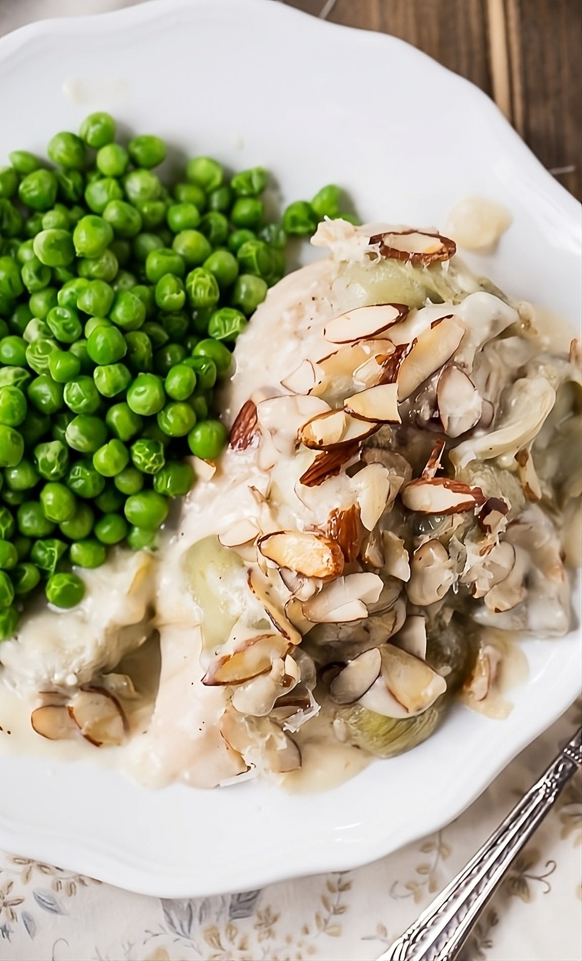 Chicken on plate with green peas.