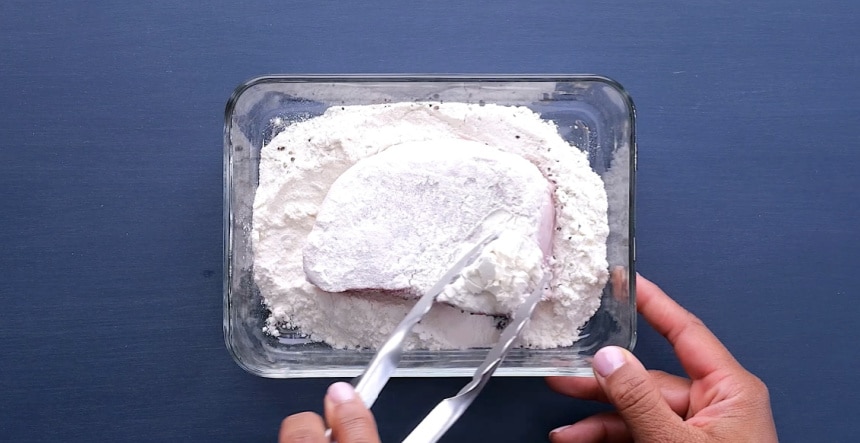 Coating pork chops in flour.