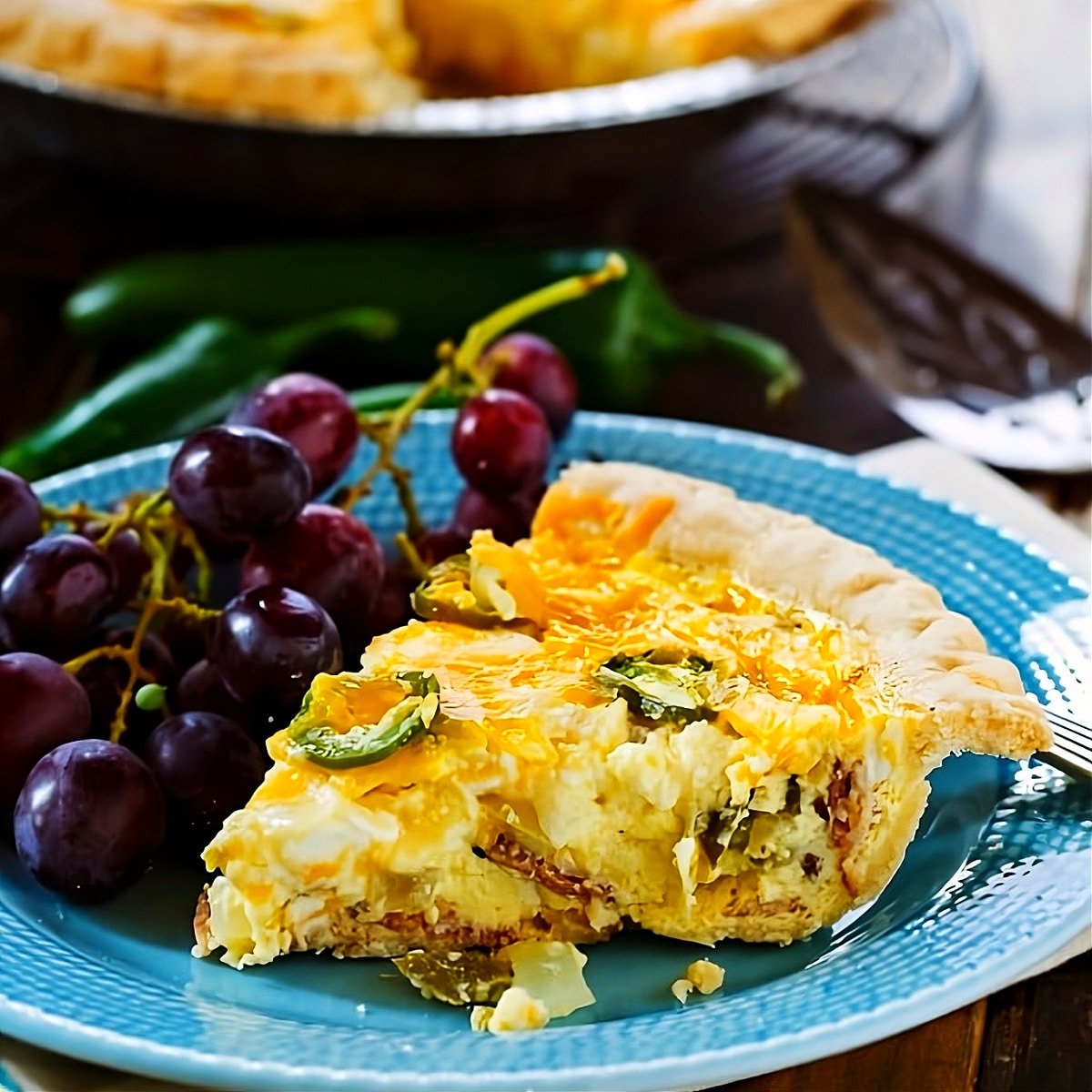 Slice of Jalapeno Popper Quiche on plate with red grapes.