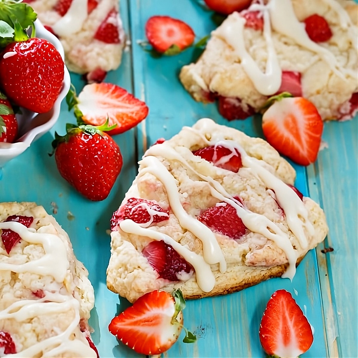 Strawberries and Cream Scones on surface with fresh strawberries.