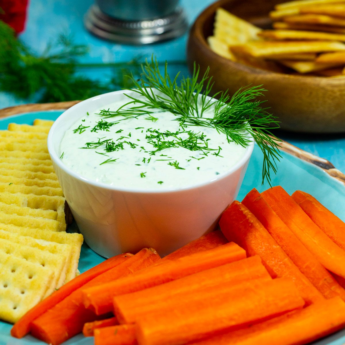Benedictine Spread in a bowl surrounded by crackers and carrot sticks.