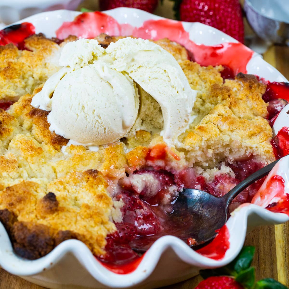 Strawberry Cobbler with a serving spoon scooping into it.