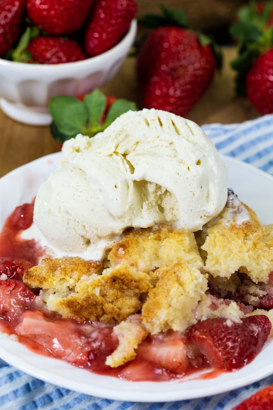 Strawberry Cobbler topped with vanilla ice cream on a plate.