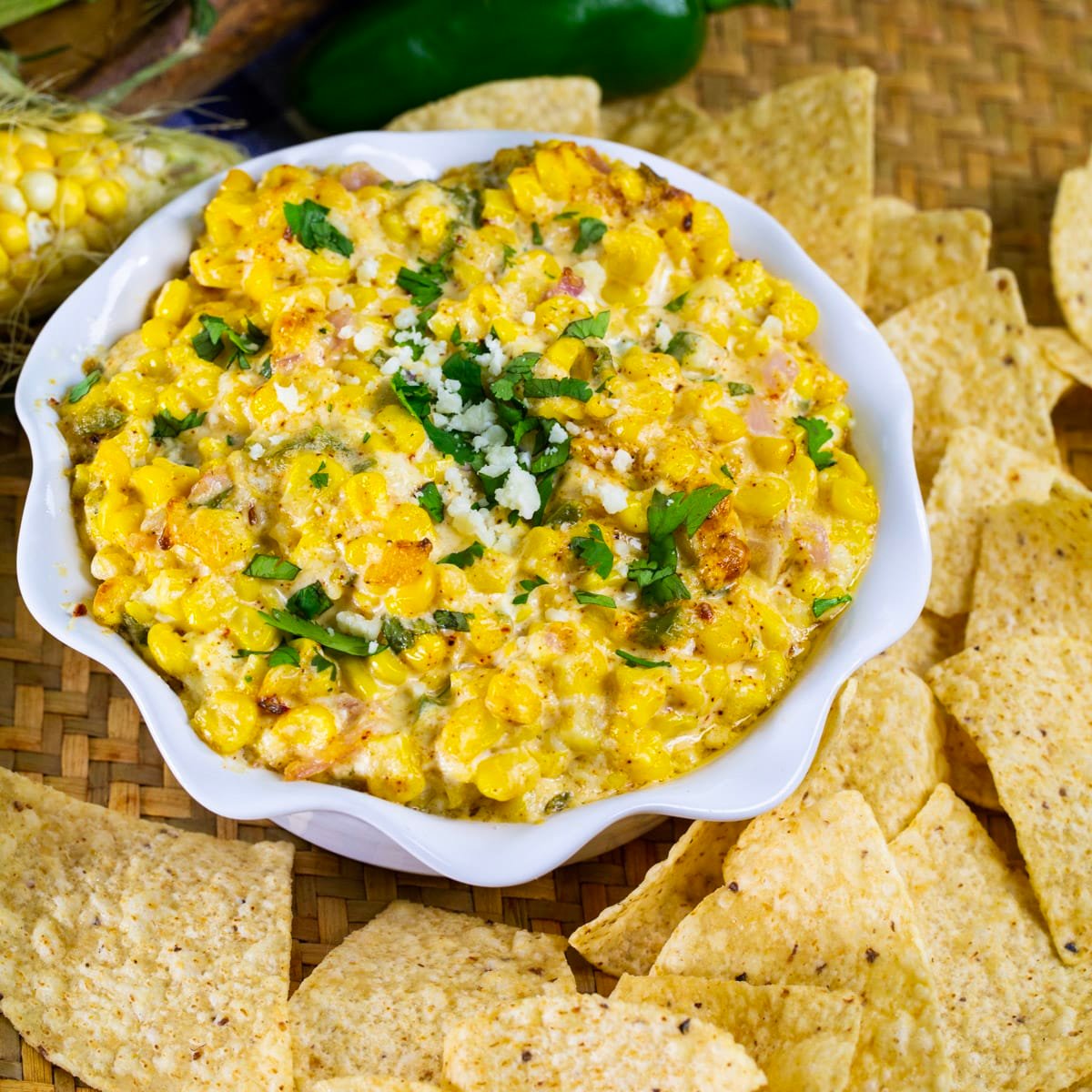 Spicy Mexican Street Corn Dip in a bowl surrounded by tortilla chips.