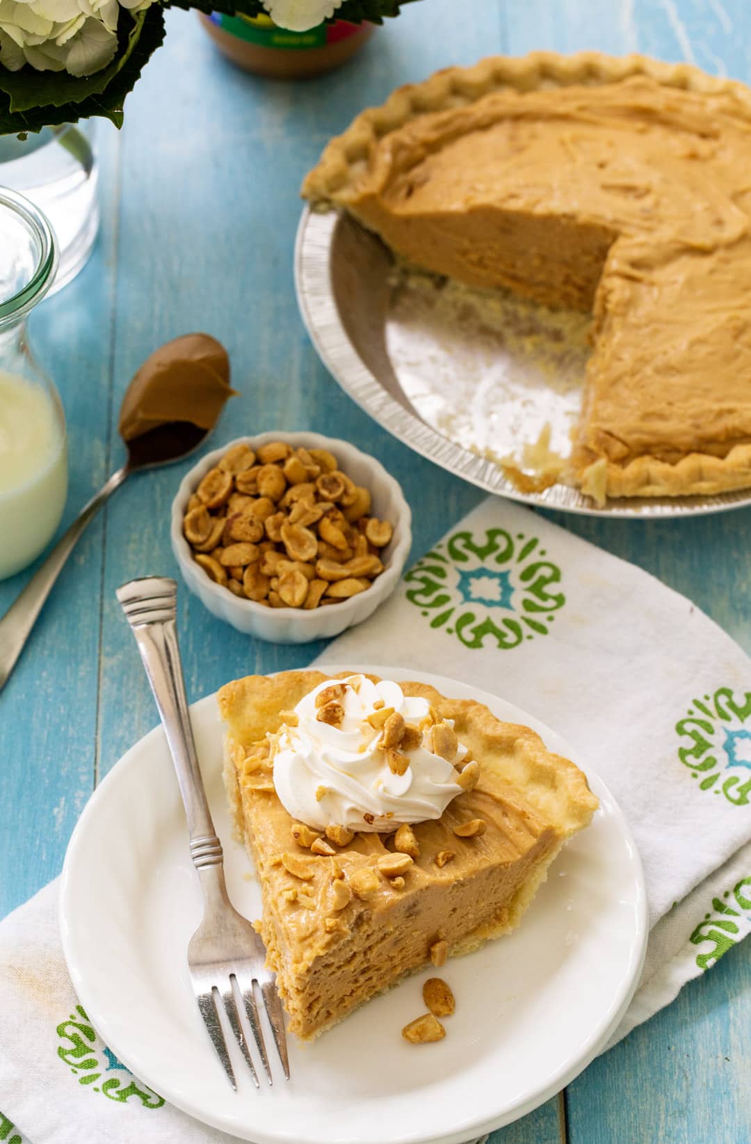 Slice of pie on a plate with rest of pie in background.