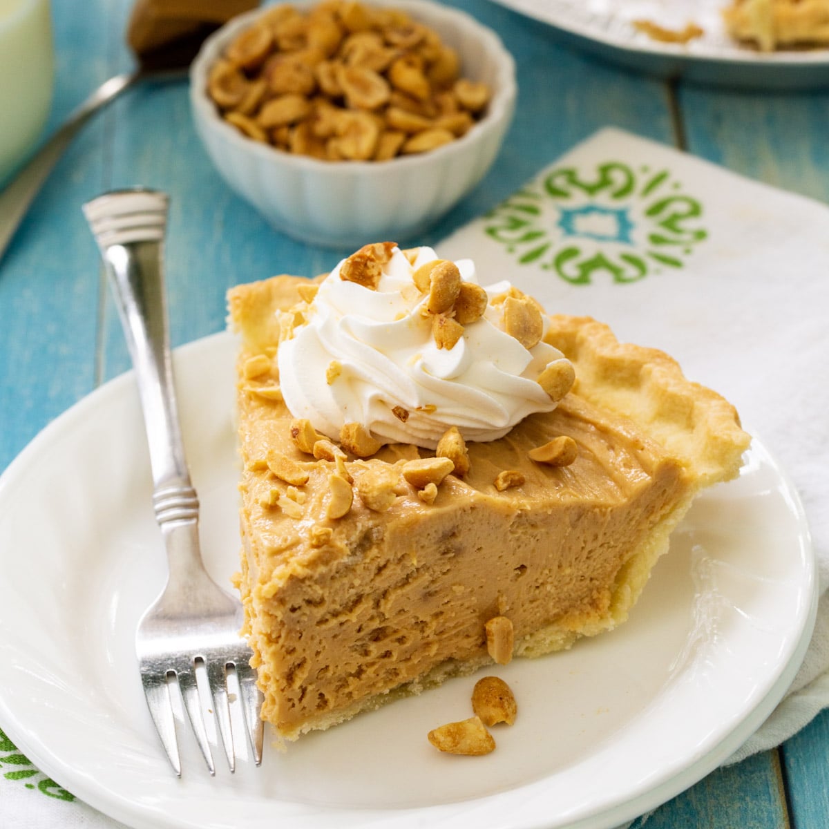 Slice of peanut butter pie topped with whipped cream and peanuts.