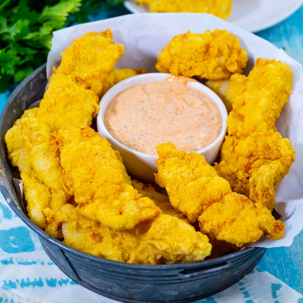 Catfish Fingers in a basket with a small bowl of Cajun Remoulade.