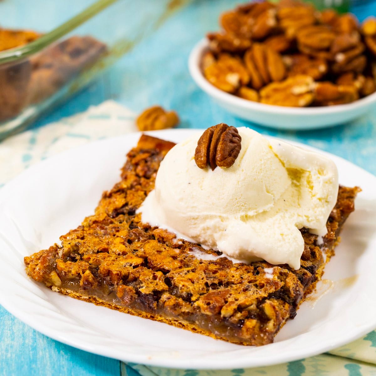 Crescent Pecan Pie Bar topped with ice cream on a plate.