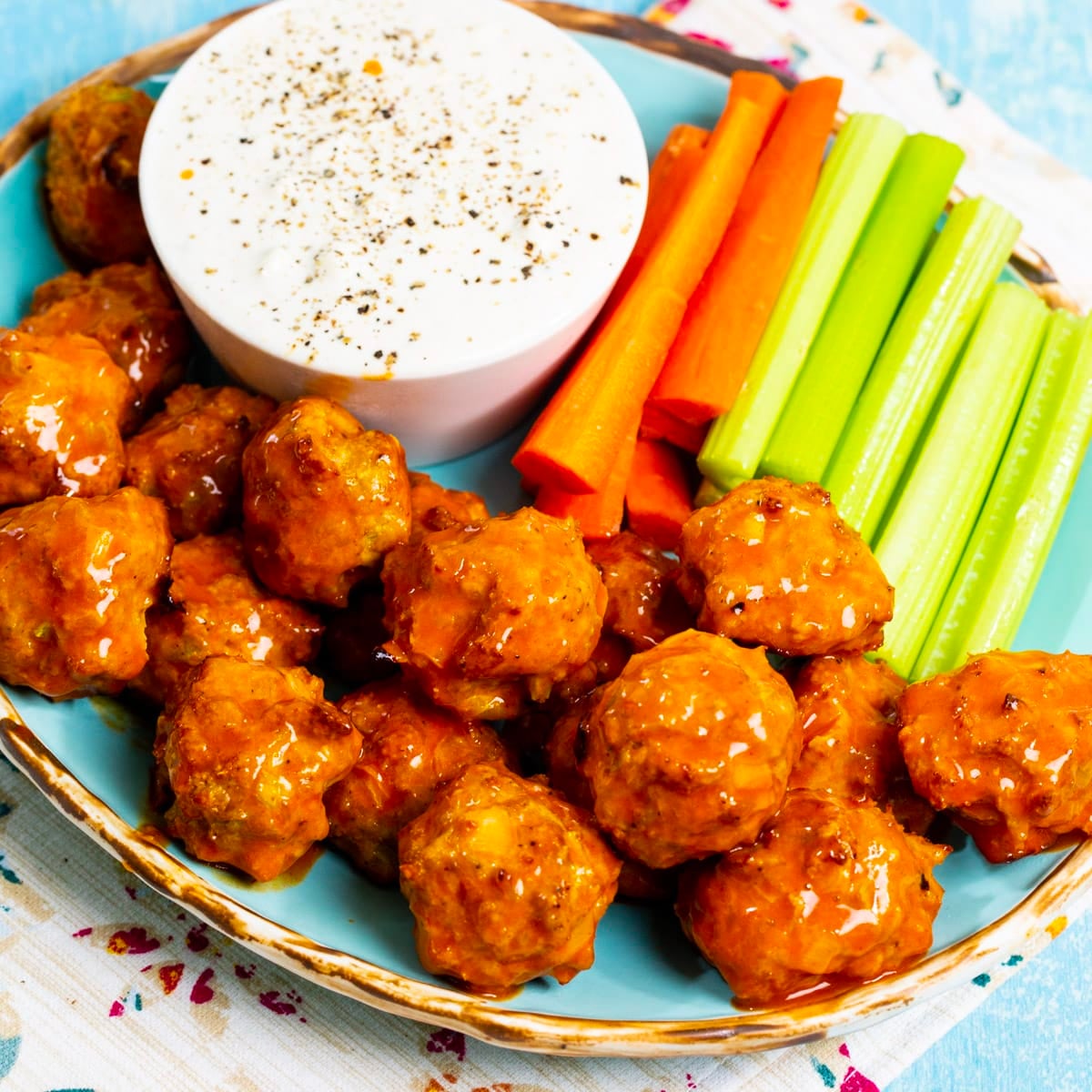 Buffalo Chicken Meatballs on plate with celery and carrot sticks.