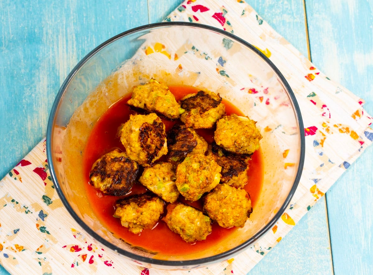 Meatballs in bowl with buffalo sauce.