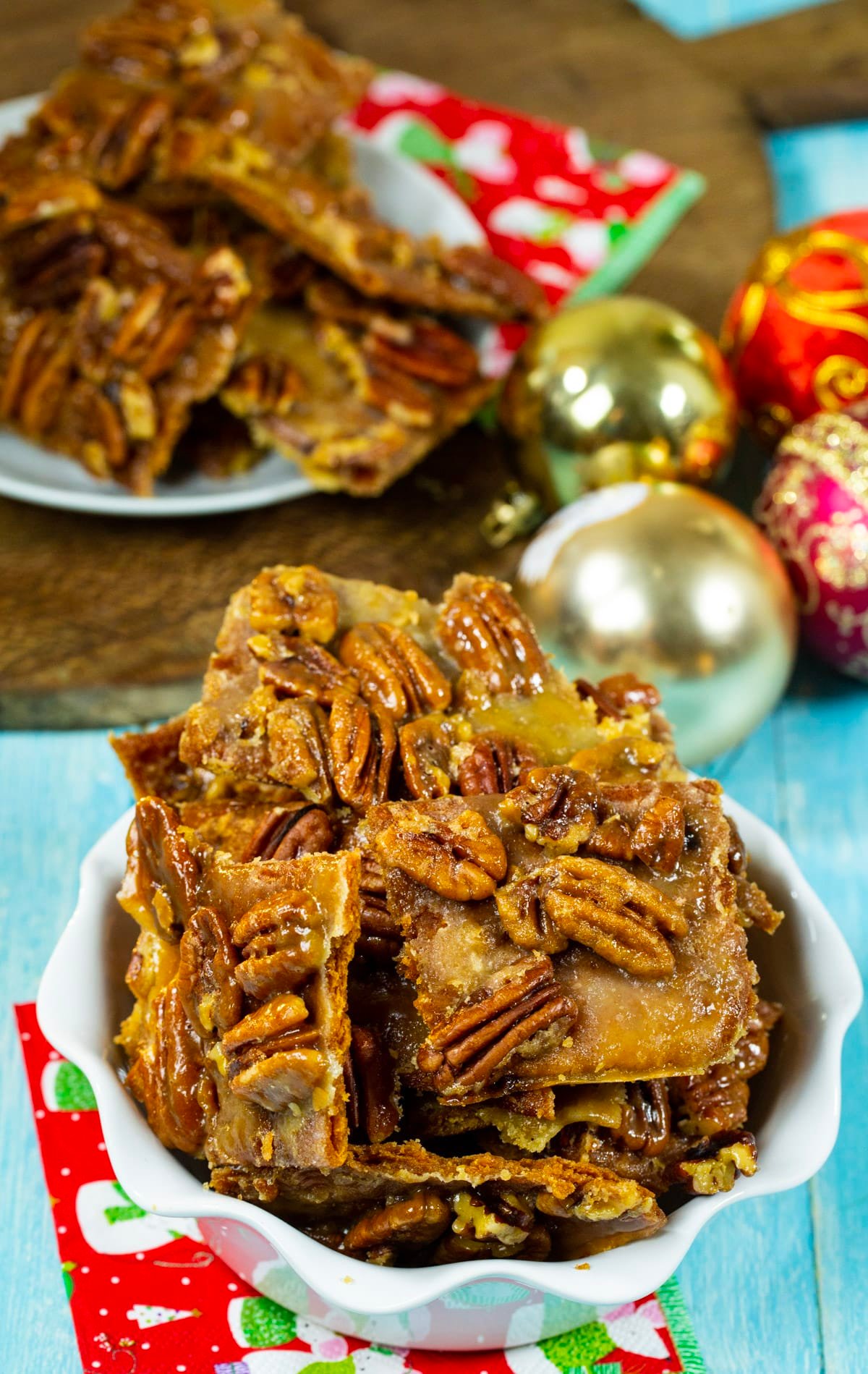 Pieces of Pecan Bark in serving dish and ornaments in background.