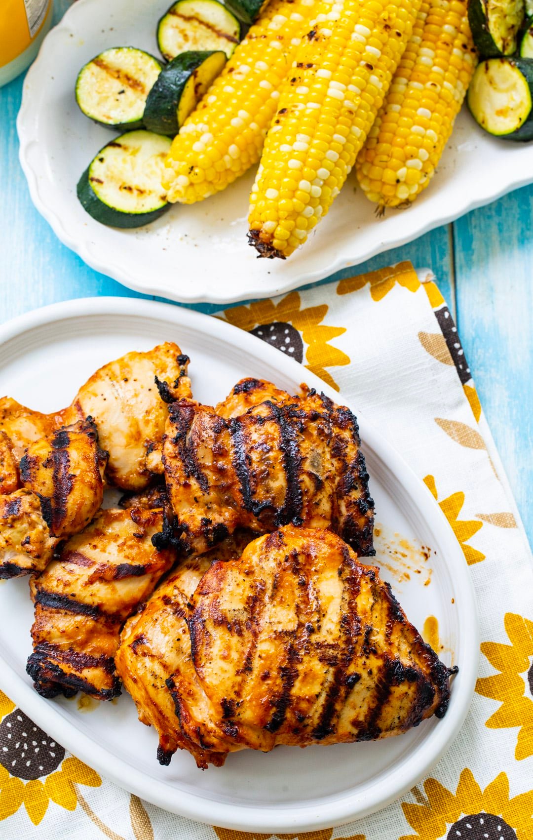 Grilled chicken on a plate and a plate of grilled vegetables.