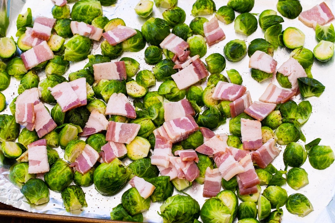 oncooked brussels sprouts and bacon on baking sheet.