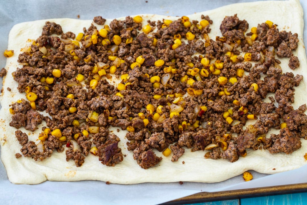 Taco filling spread on pizza dough.