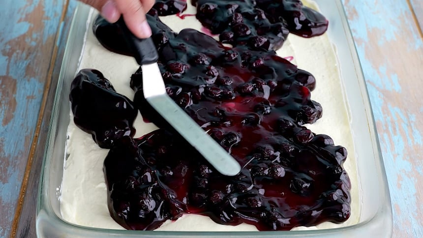 Spreading blueberry pie filling over lemon layer.