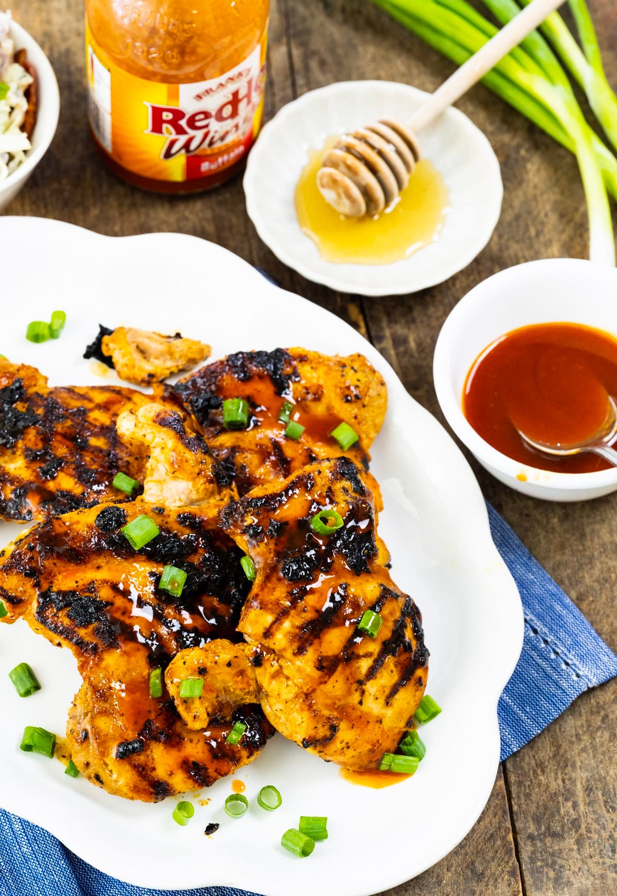 Chicken on platter and bowl of honey and hot sauce.