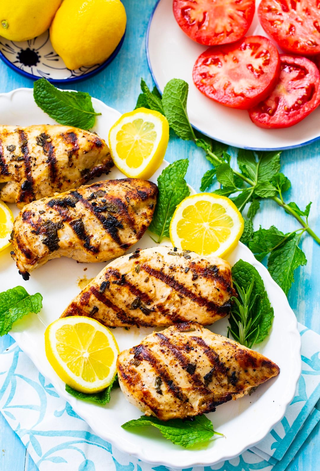 Grilled Chicken on a serving plate with lemon slices and fresh mint.