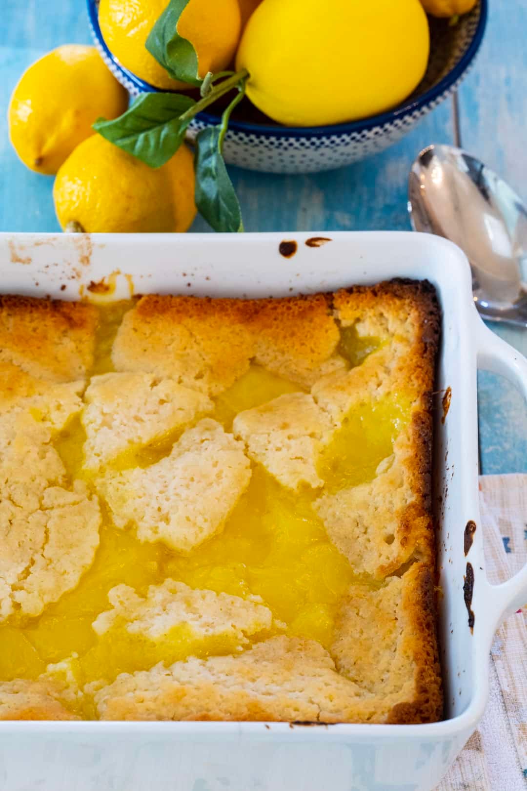 Lemon Cobbler in a baking dish and bowl full of lemons.