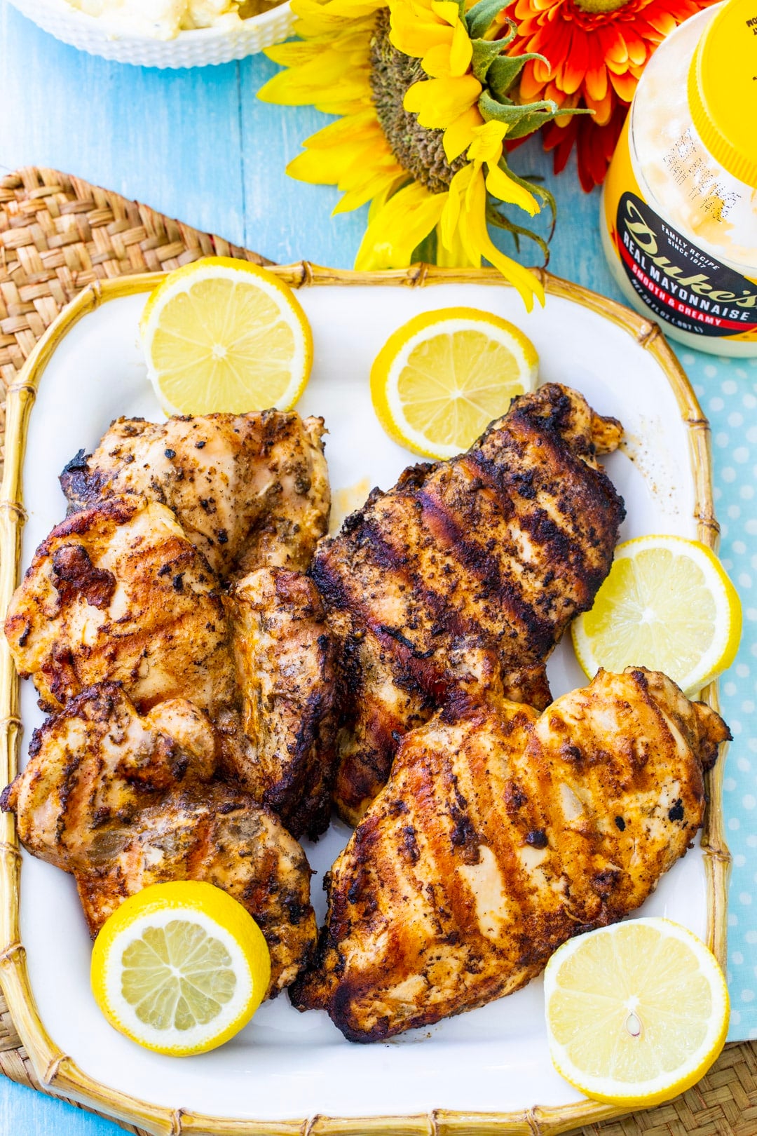 Mayonnaise Marinated Grilled Chicken on a serving platter with lemon slices and a jar of mayonnaise.