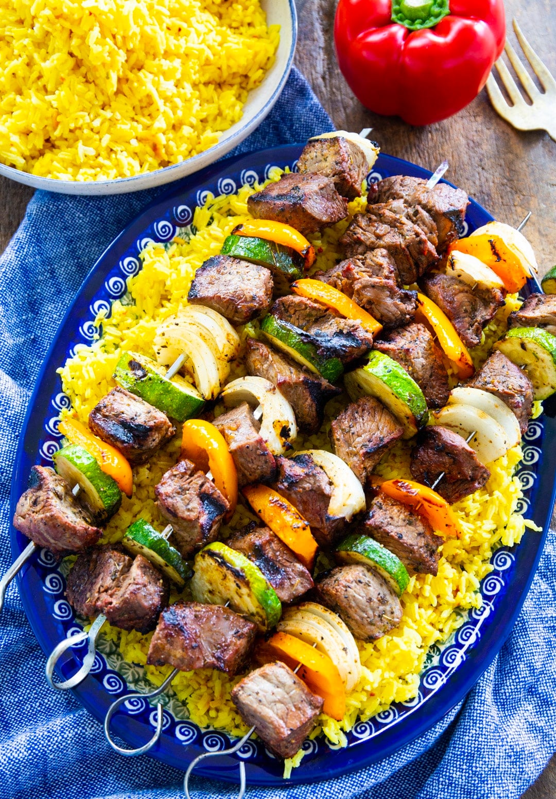 Grilled Beef Shish Kabobs on a serving platter and a bowl full of rice.